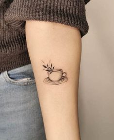 a woman's arm with a small cup and saucer tattoo on the left forearm