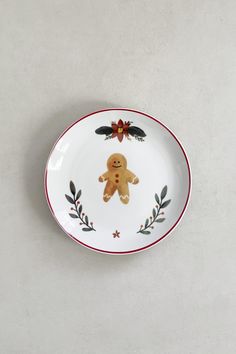 a white plate with a brown teddy bear on the front and red trim around the edge