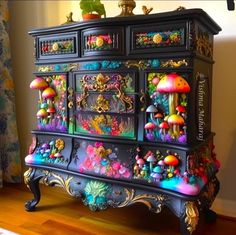 an ornate dresser with many colorful decorations on the top and bottom drawers, painted black