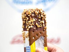 a person holding an ice cream cone with nuts on it