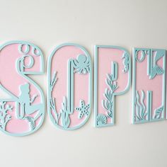 the letters are cut out of paper and placed in front of a white wall with pink and blue accents