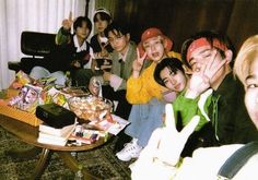 a group of young people sitting around a table with food on top of it and posing for the camera