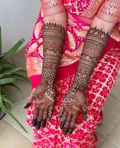 a woman with henna tattoos on her hands and arms, holding onto the ground