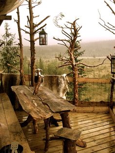 a wooden deck with benches and trees in the background, looking out over an open field