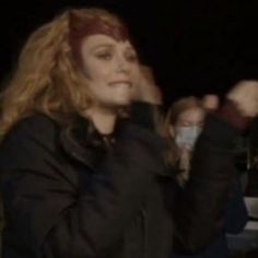 a woman with red hair standing in front of a crowd