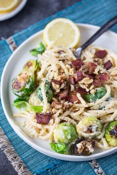 a white plate topped with pasta covered in bacon and brussel sprouts