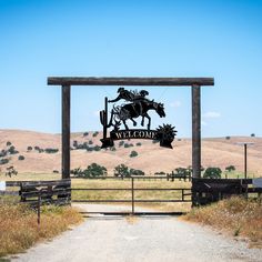 a sign for a ranch with a horse and rider on the front is in an open field