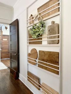 a white wall with wooden shelves and plants on it's sides, in front of a door