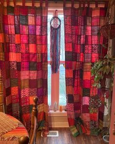 a bed room with a neatly made bed next to a window covered in colorful curtains