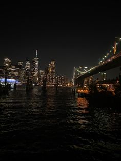 the city skyline is lit up at night as seen from across the water in new york