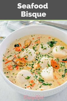 a white bowl filled with seafood chowder next to a spoon and napkin on top of a table