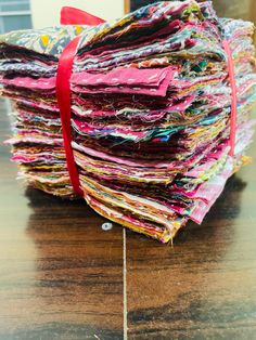 a pile of fabric sitting on top of a wooden table next to a red ribbon