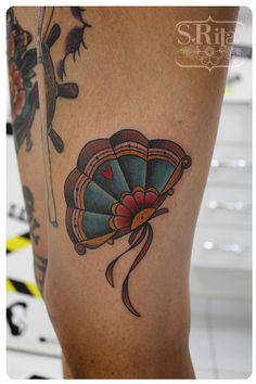 a woman's leg with tattoos on it and a fan in the middle of her leg