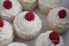 there are many cupcakes with white frosting and raspberries on top