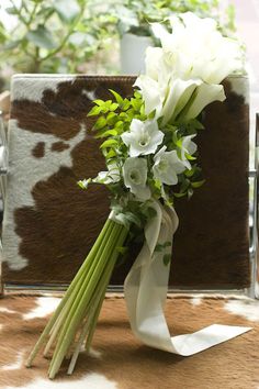 a bouquet of white flowers sitting on top of a cow print table cloth next to a chair