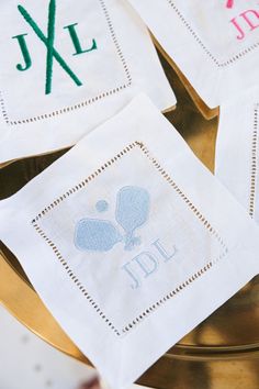 four monogrammed napkins on top of a gold plate with the letters j and l