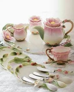 pink flowers are sitting on the table next to teacups and spoons with forks