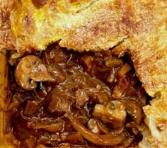 a close up view of some food in a pie crust with meat and mushrooms on it