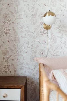 a bedroom with floral wallpaper and a white lamp next to the bed in front of it