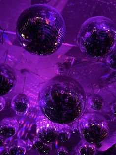 disco balls hanging from the ceiling in a room with purple lighting and mirrors on it