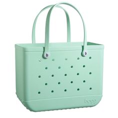 a green tote bag with holes on the front and side, sitting against a white background