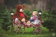 a baby sitting in a wagon with a teddy bear