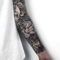 a man's arm with flowers and leaves tattooed on the left side of his arm