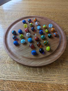 a wooden plate filled with lots of different colored marbles on top of a table