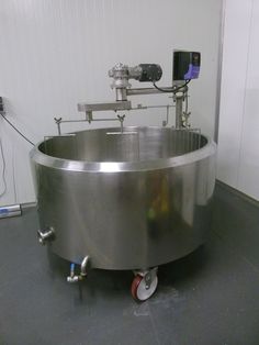 a large stainless steel tank sitting on top of a gray floor next to a white wall