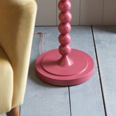 a pink table lamp sitting on top of a wooden floor next to a yellow chair