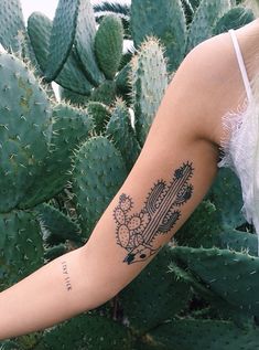 a woman's arm with a cactus tattoo on the left side of her arm