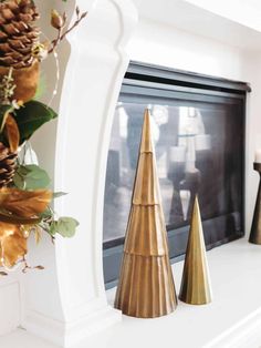 three gold christmas trees sitting on top of a white mantle