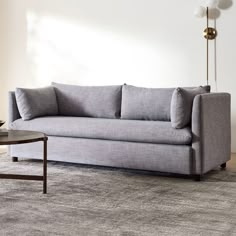 a gray couch sitting on top of a rug in a living room next to a table