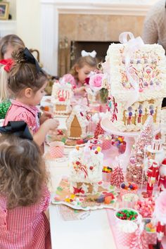 several children are standing around a table with many cakes and candies