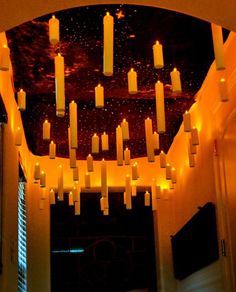 many lit candles are in the middle of a room that is decorated with orange lights