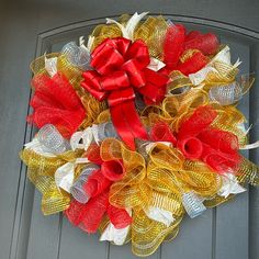 a red, white and yellow mesh wreath on the front door is decorated with bows