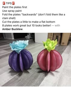 two vases with flowers on them sitting on the floor in front of a box