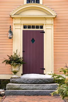 a red door is on the side of a pink house with steps leading up to it