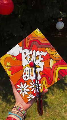 someone holding up a colorful graduation cap with the words peace out written in white letters on it