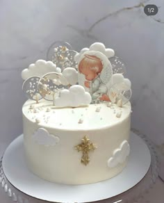 a white cake decorated with an angel and clouds on it's side, sitting on top of a silver platter