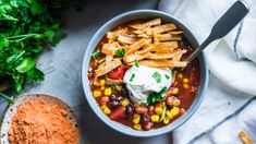 a bowl of mexican soup with tortilla chips and sour cream on the side