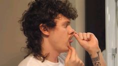 a man with curly hair is brushing his teeth