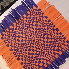 an array of orange and purple sticks are arranged on a white tablecloth with black trim