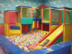 an indoor play area with lots of balls and toys on the ground, in a children's playroom