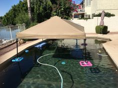 an outdoor swimming pool with water toys in it and a canopy over the pool area