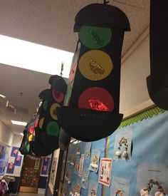 a traffic light hanging from the side of a wall next to a bulletin board with pictures on it