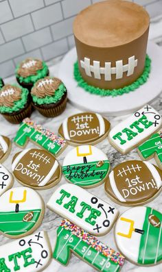 decorated cookies and cupcakes for a football themed baby shower are on the table