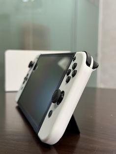 an electronic device sitting on top of a wooden table next to a white box with black buttons