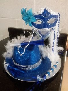 a masquerade hat and mask on top of a blue plate with white feathers