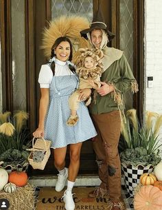 a man and woman dressed up as scarecrows posing for a photo in front of a door